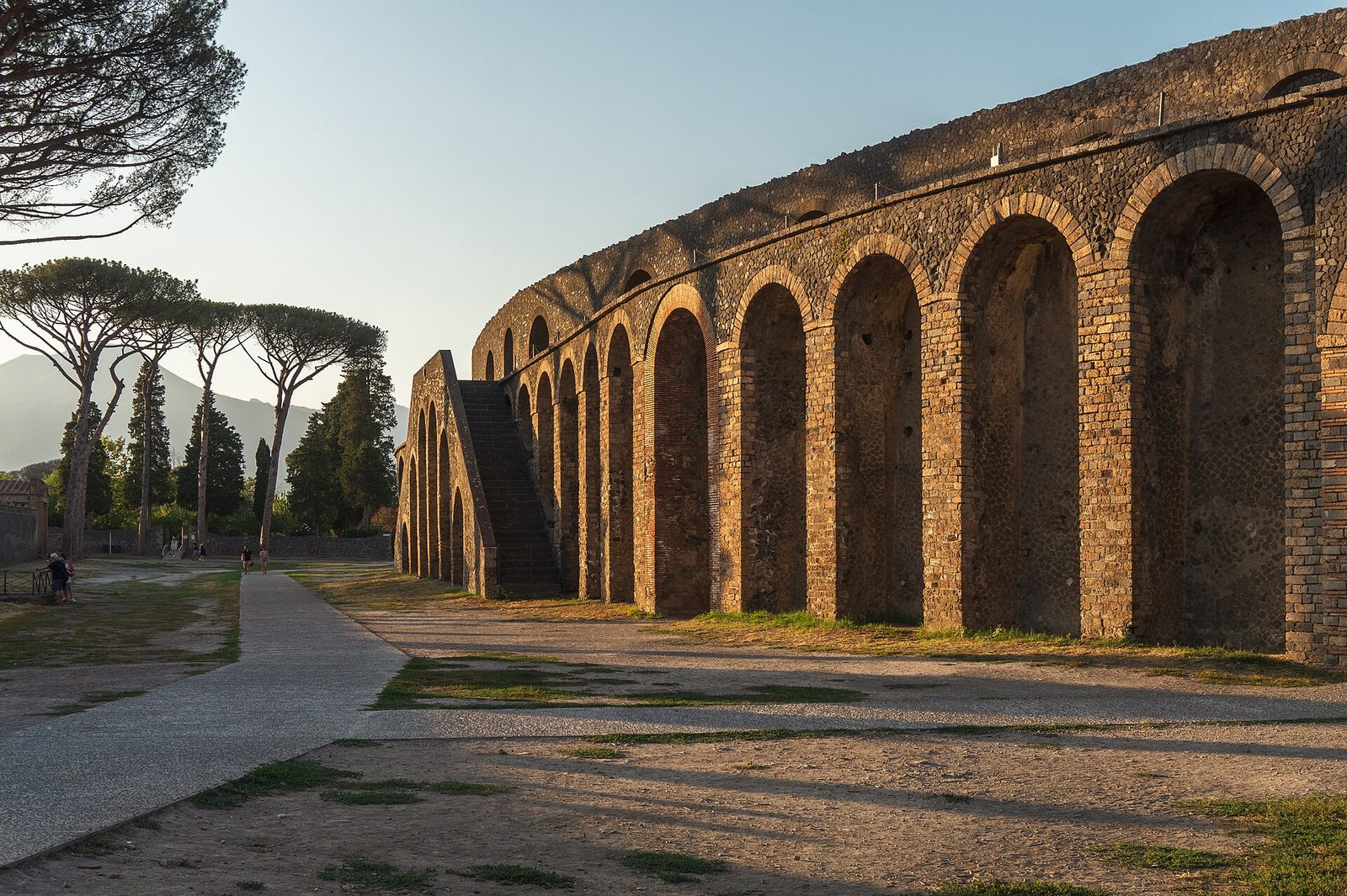 Vista externa do Anfiteatro de Pompeia ao entardecer, com o Monte Vesúvio ao fundo