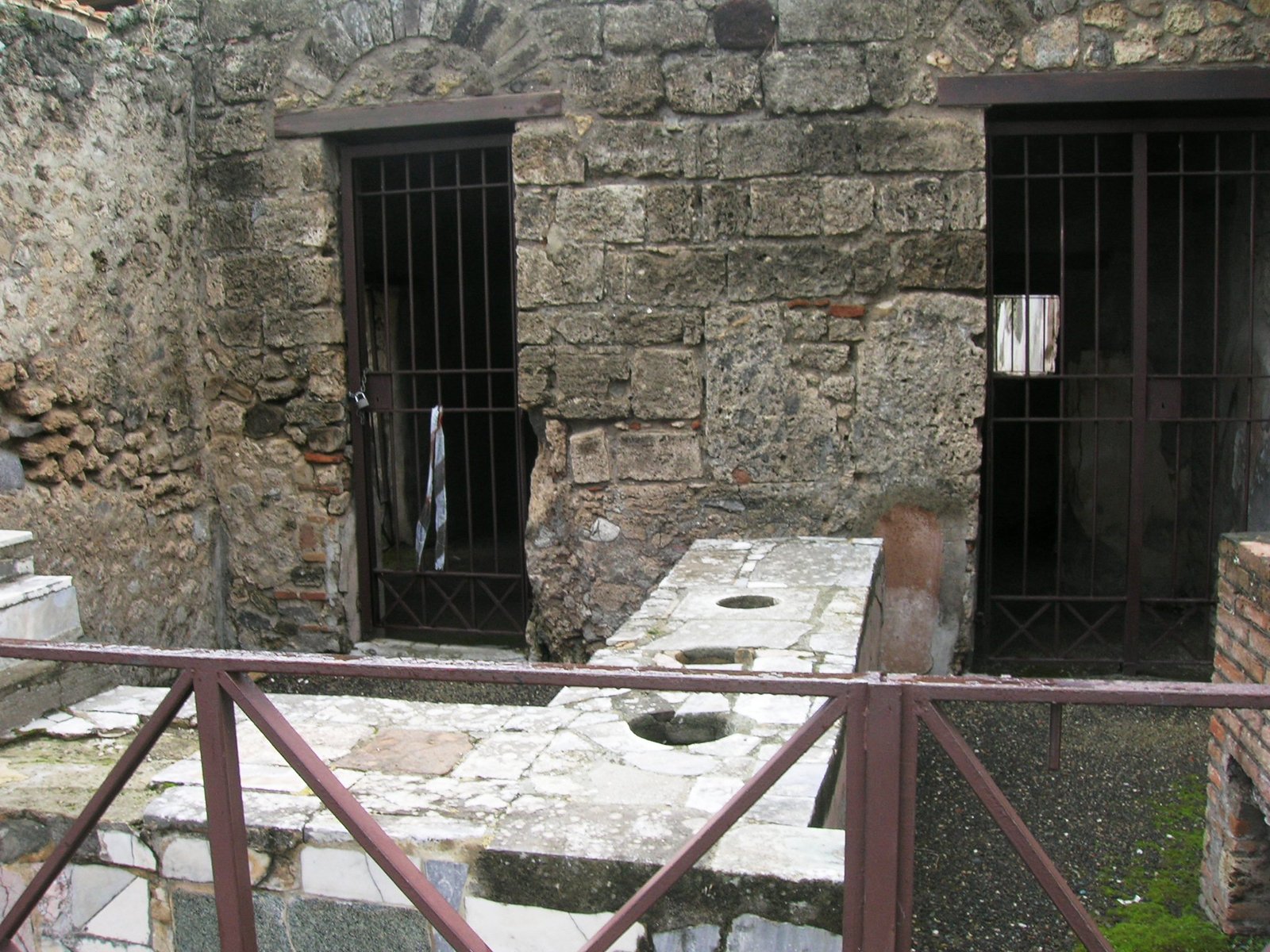 Interior da antiga taverna romana (caupona) na Via di Mercurio, Pompeia, com afrescos na parede